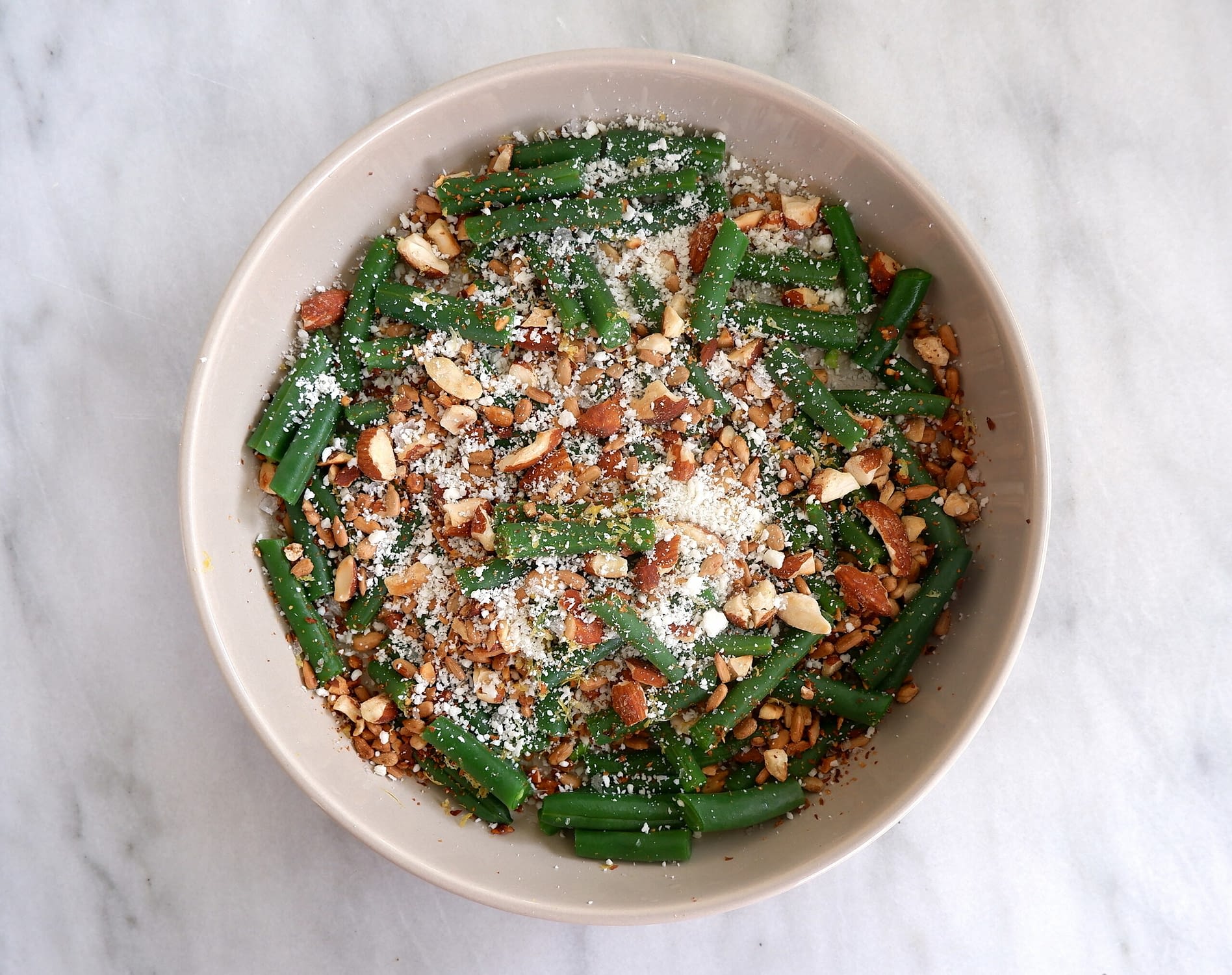 Plate of green beans with almonds, lemon zest, and cotija cheese.